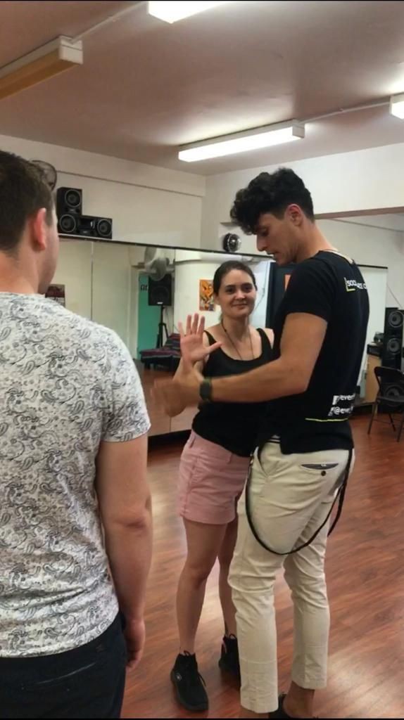 People dancing together in a dance studio with wooden floors and mirrors on the walls.