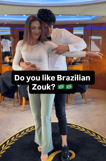 Two people dancing Brazilian Zouk in a room with a wooden interior and blue lighting.